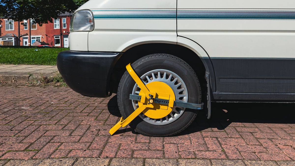 Yellow immobilizer locked to front wheel of parked campervan